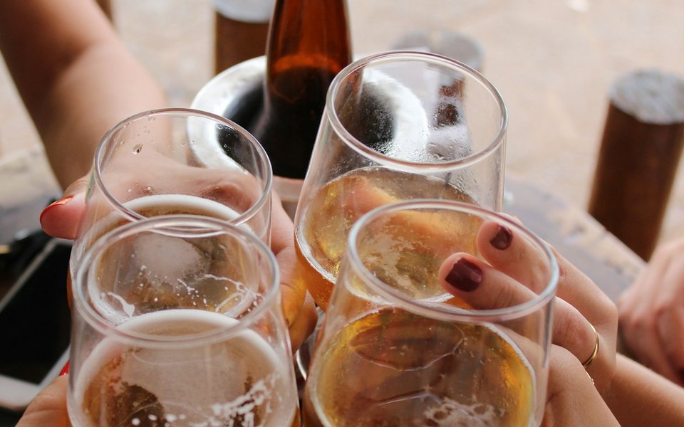 貸会議室での懇親会で乾杯するようす。ビールの入ったグラスを合わせる4人の手